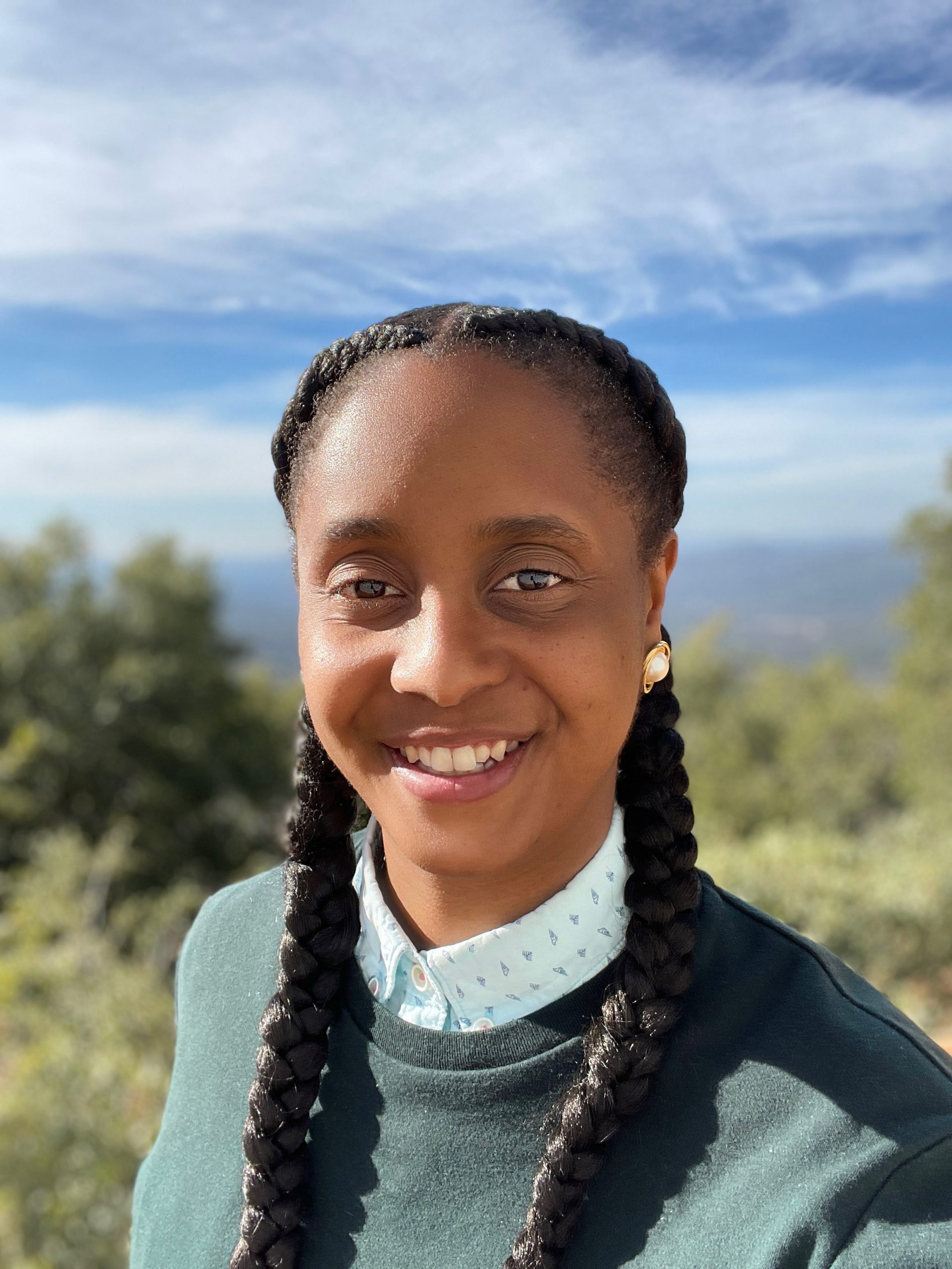 headshot of Jay Gash, a black queer person with two thick braids outdoors