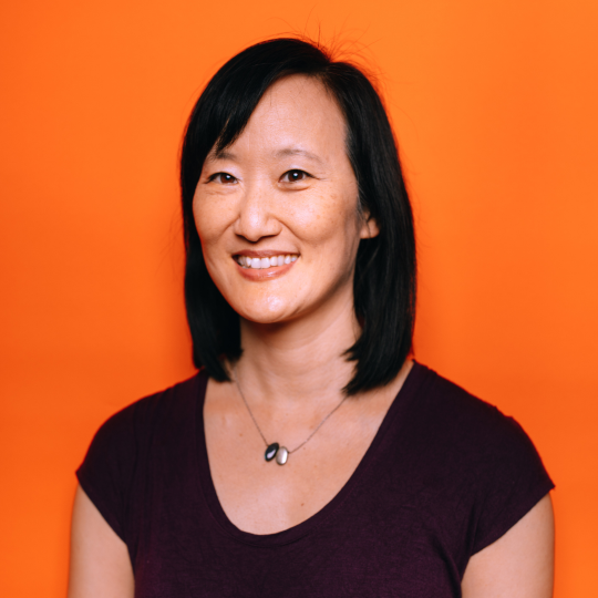 headshot of Jennifer Huang in a black tshirt against an orange background